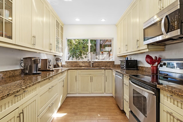 kitchen with appliances with stainless steel finishes, a sink, and cream cabinets