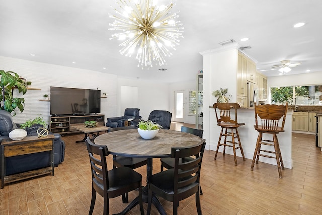 dining area featuring ceiling fan with notable chandelier, a wealth of natural light, and light wood-type flooring