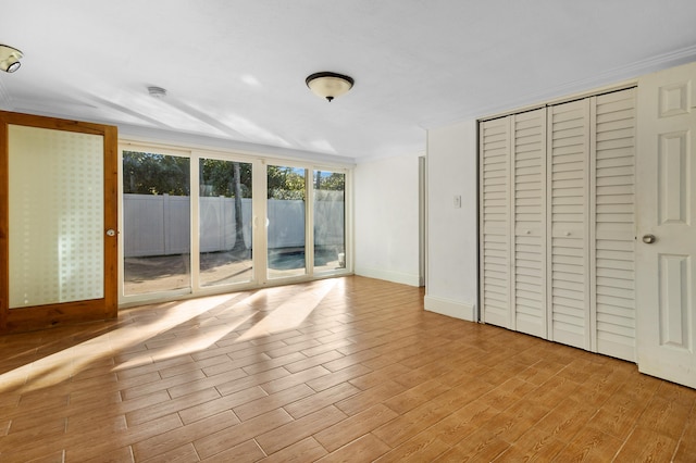 unfurnished bedroom featuring crown molding, access to exterior, and light wood-type flooring