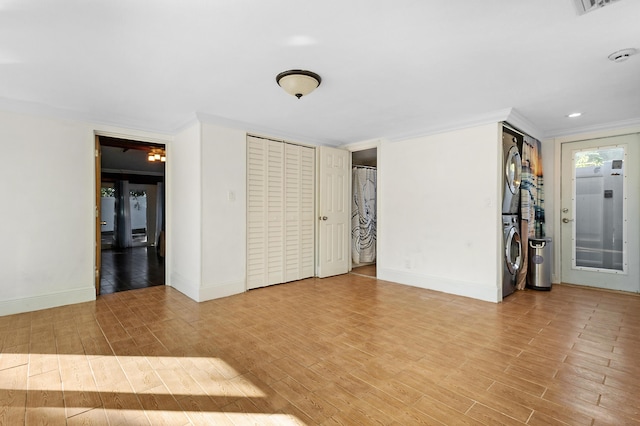 unfurnished room featuring stacked washer / dryer, crown molding, and light wood-type flooring