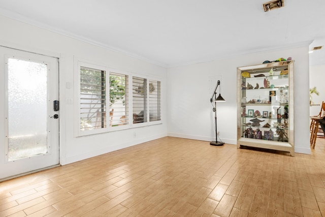 interior space with crown molding, baseboards, visible vents, and light wood-style floors