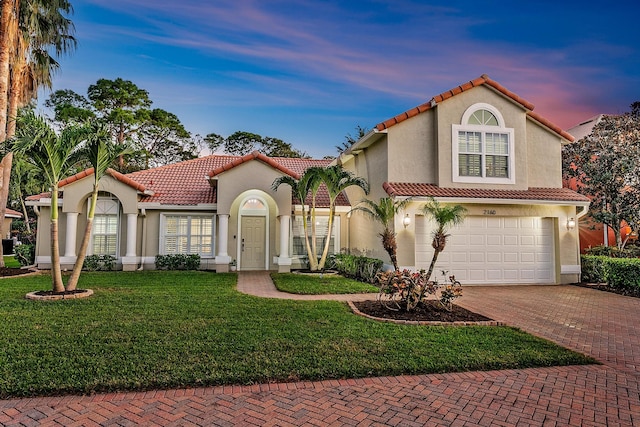 mediterranean / spanish-style home featuring a garage and a lawn