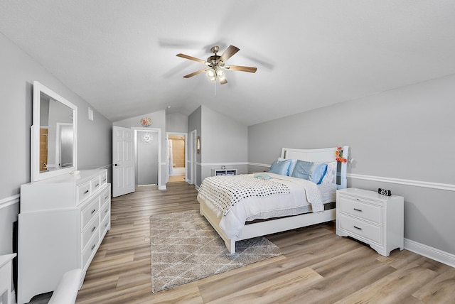 bedroom featuring ceiling fan, lofted ceiling, ensuite bath, and light wood-type flooring