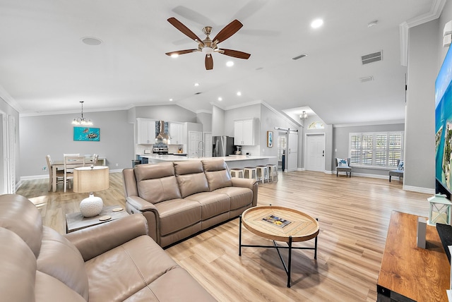 living room with visible vents, light wood-type flooring, vaulted ceiling, ornamental molding, and ceiling fan with notable chandelier