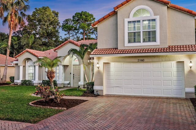 mediterranean / spanish house featuring a garage and a lawn