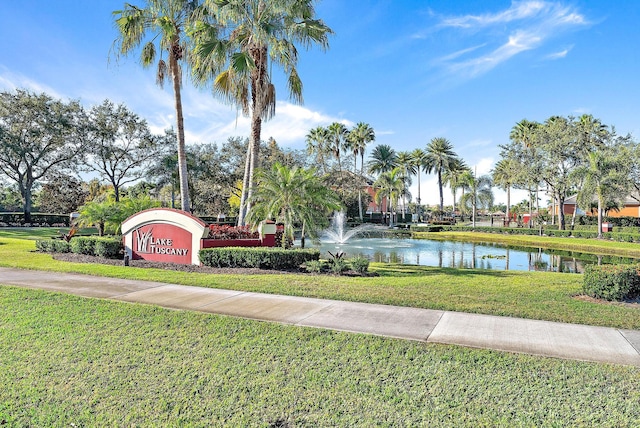 view of property's community with a water view and a lawn