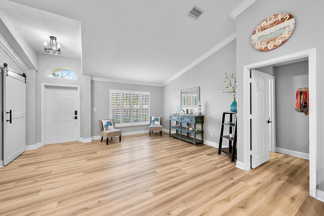 living room featuring vaulted ceiling, a barn door, ceiling fan with notable chandelier, and crown molding