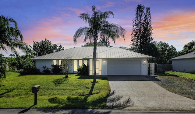 single story home featuring a garage and a yard