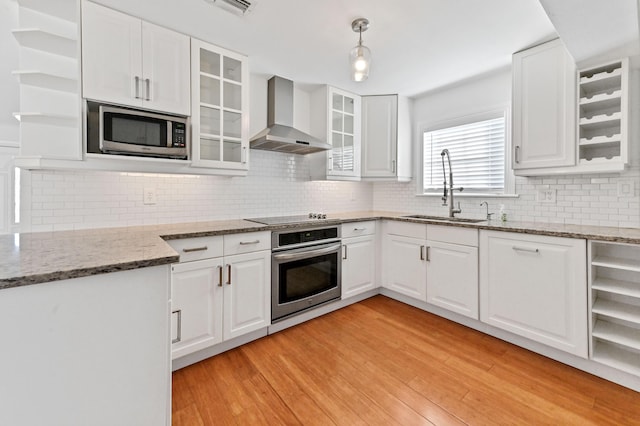 kitchen featuring white cabinetry, sink, wall chimney range hood, and appliances with stainless steel finishes