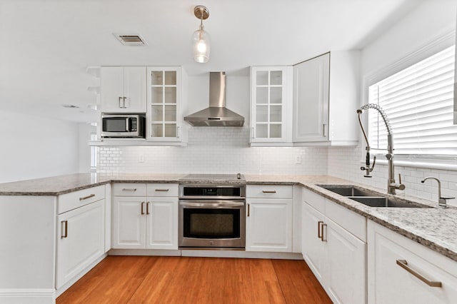 kitchen featuring white cabinets, sink, wall chimney exhaust hood, and appliances with stainless steel finishes