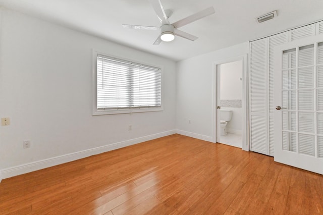 unfurnished bedroom featuring light hardwood / wood-style floors, ensuite bath, and ceiling fan