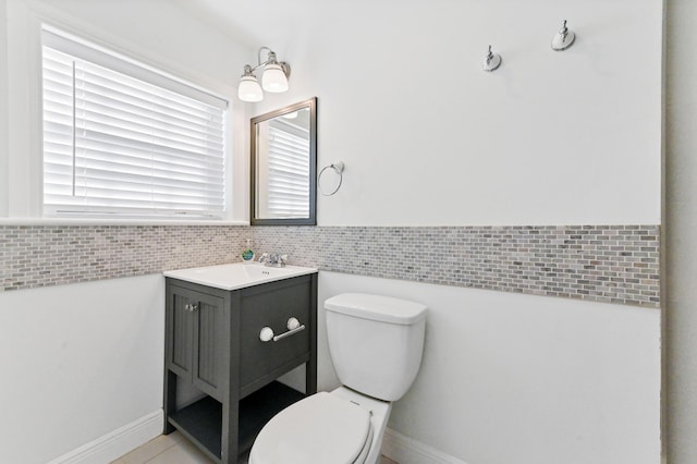 bathroom featuring plenty of natural light, toilet, tile walls, and vanity