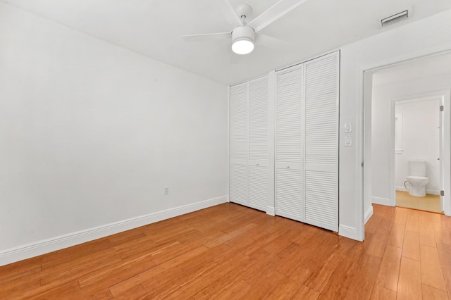 unfurnished bedroom featuring ceiling fan, ensuite bathroom, and hardwood / wood-style flooring