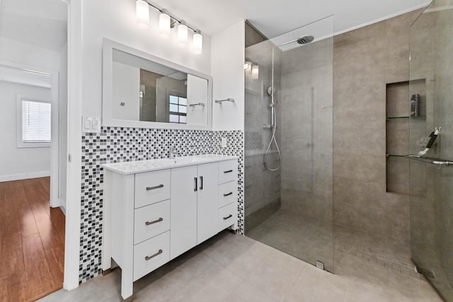 bathroom featuring tiled shower, wood-type flooring, vanity, and backsplash