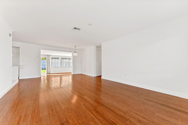 unfurnished living room with hardwood / wood-style floors and an inviting chandelier