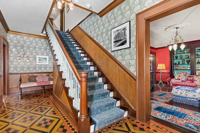 stairway with ornamental molding and a chandelier