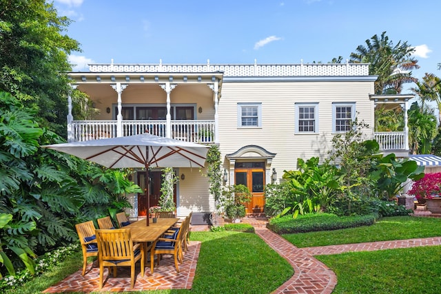 view of front of property with a balcony, a patio, and a front yard