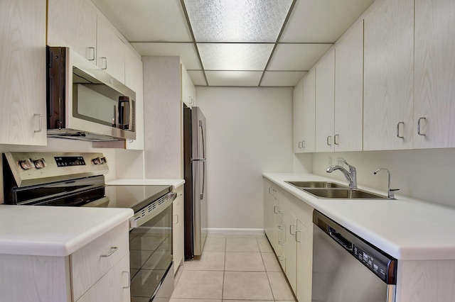 kitchen with appliances with stainless steel finishes, light tile patterned floors, a drop ceiling, and sink