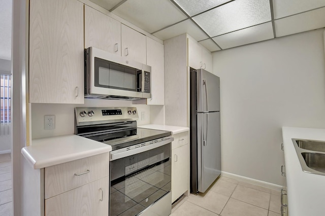 kitchen featuring a paneled ceiling, light tile patterned floors, sink, and appliances with stainless steel finishes