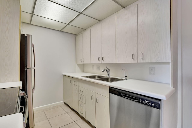 kitchen with a paneled ceiling, sink, light tile patterned floors, and stainless steel appliances