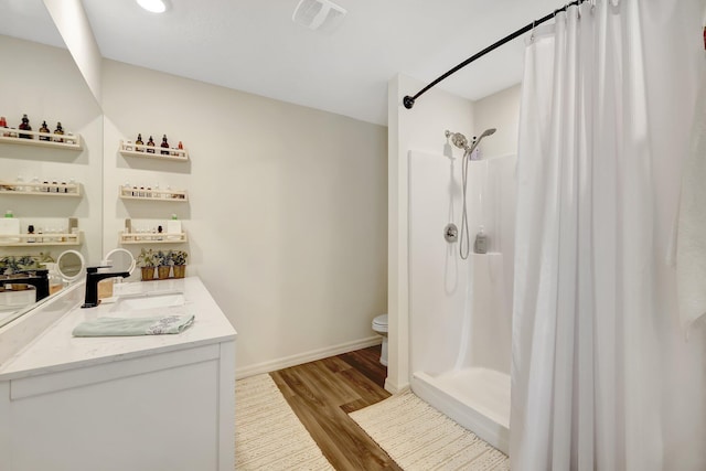 bathroom with walk in shower, toilet, vanity, and hardwood / wood-style flooring