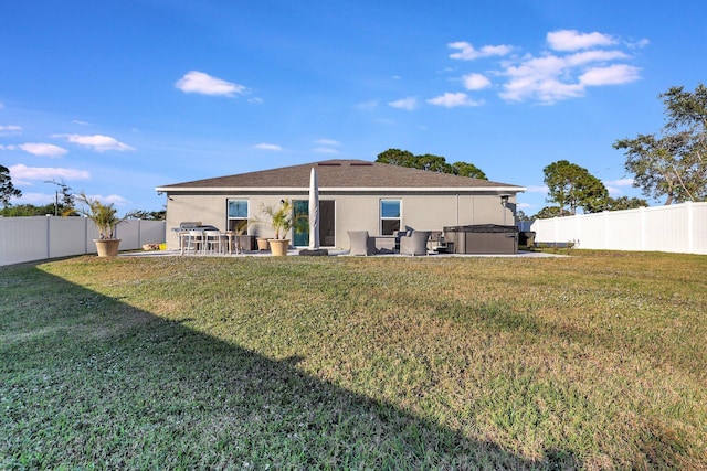 back of property featuring a yard, a hot tub, and a patio area