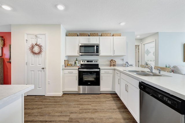 kitchen with white cabinets, light hardwood / wood-style floors, sink, and appliances with stainless steel finishes