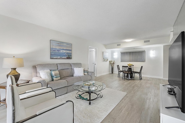 living room with a textured ceiling and light hardwood / wood-style flooring