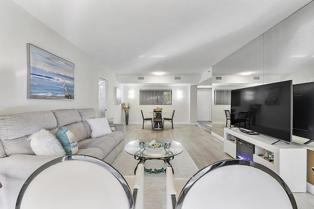 living room with a textured ceiling and light hardwood / wood-style flooring