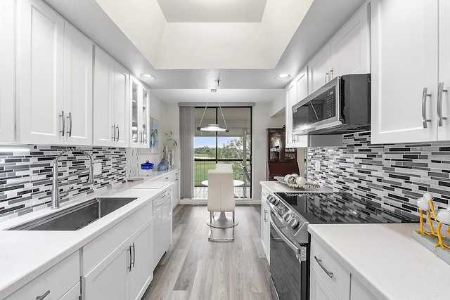 kitchen featuring light wood-type flooring, stainless steel appliances, white cabinetry, and backsplash