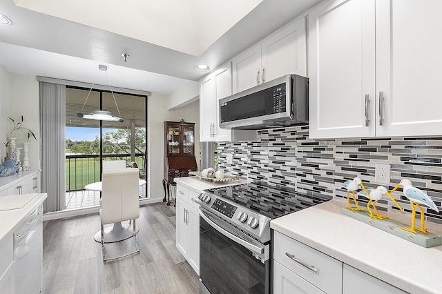 kitchen featuring white cabinets, appliances with stainless steel finishes, light hardwood / wood-style floors, and decorative light fixtures