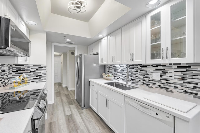 kitchen featuring sink, stainless steel appliances, light hardwood / wood-style floors, decorative backsplash, and white cabinets