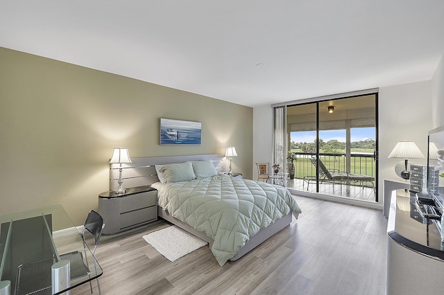 bedroom featuring expansive windows, access to exterior, and light hardwood / wood-style flooring