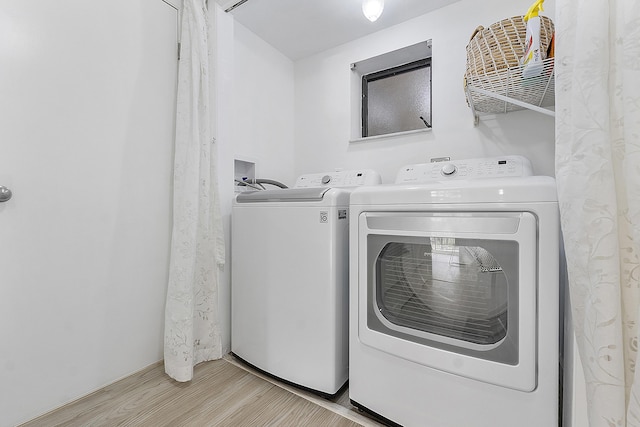 laundry room featuring washer and clothes dryer and light hardwood / wood-style flooring