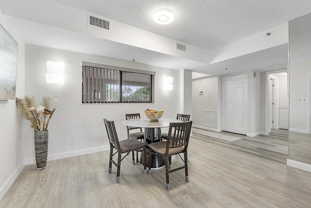 dining room featuring a textured ceiling and light hardwood / wood-style flooring