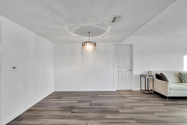 dining room featuring a textured ceiling, a notable chandelier, and hardwood / wood-style flooring