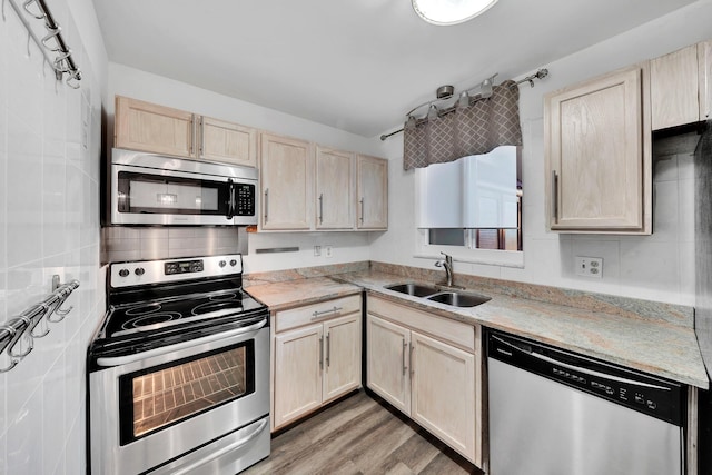 kitchen with light brown cabinetry, light wood-type flooring, stainless steel appliances, and sink