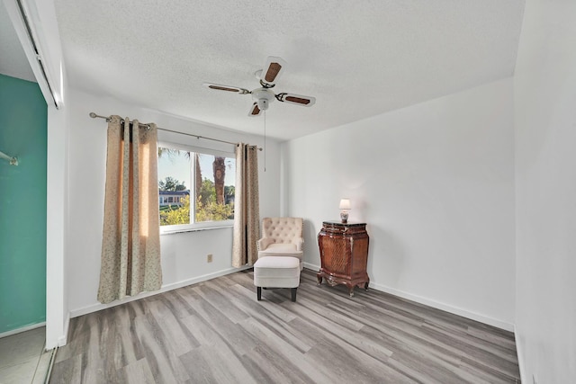 unfurnished room featuring ceiling fan, light hardwood / wood-style flooring, and a textured ceiling