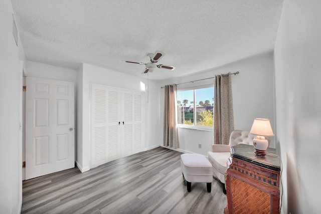 sitting room featuring hardwood / wood-style flooring, a textured ceiling, and ceiling fan