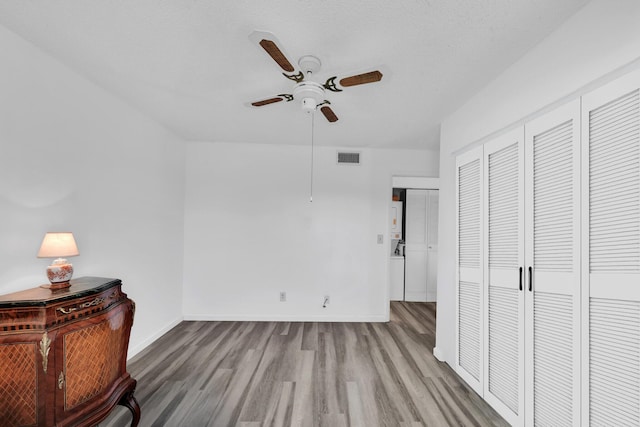 sitting room featuring ceiling fan, wood-type flooring, and a textured ceiling