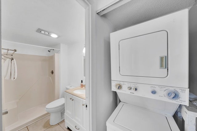 laundry area with light tile patterned flooring, stacked washing maching and dryer, and sink