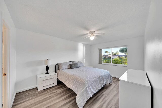 bedroom featuring ceiling fan, a textured ceiling, and light hardwood / wood-style floors