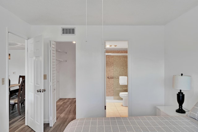 bedroom with hardwood / wood-style floors and ensuite bath