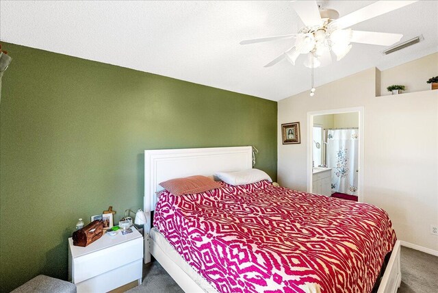 carpeted bedroom featuring a textured ceiling, ensuite bath, ceiling fan, and lofted ceiling