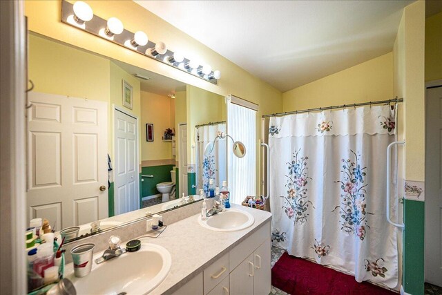 bathroom with a shower with shower curtain, vanity, toilet, and vaulted ceiling