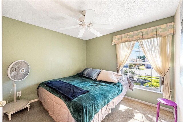 carpeted bedroom featuring a textured ceiling and ceiling fan