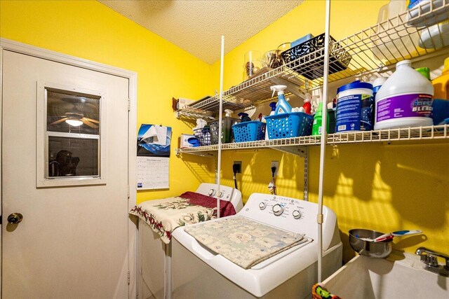 clothes washing area with independent washer and dryer, a textured ceiling, and sink