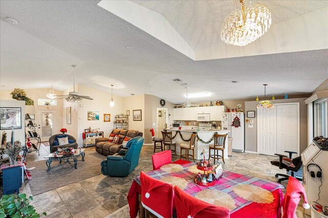 dining area featuring ceiling fan with notable chandelier, a textured ceiling, and vaulted ceiling