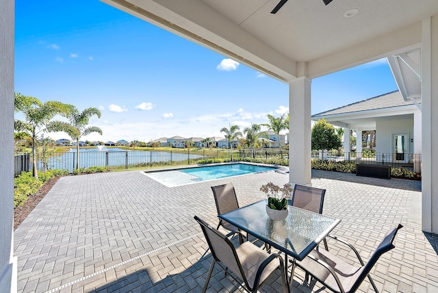 view of patio featuring ceiling fan, a water view, and a fenced in pool