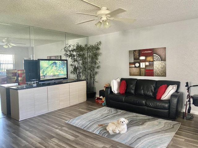 living room featuring hardwood / wood-style flooring, ceiling fan, and a textured ceiling